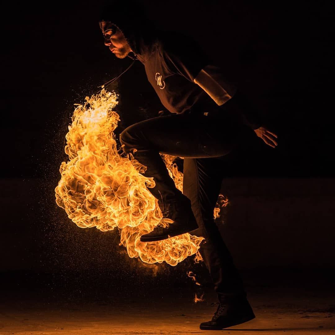 Genou levé, une boule de feu roule sous la jambe en volutes dorées, de nuit au Palais de Tokyo