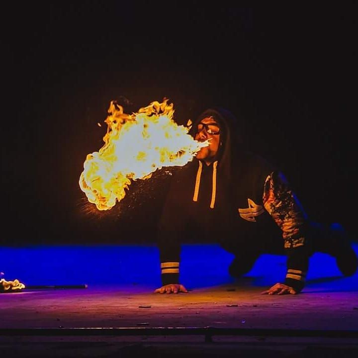 En appui sur les mains comme pour une pompe, le cracheur souffle une flamme vers l’avant, scène bleue du Fire Life Fest 2018