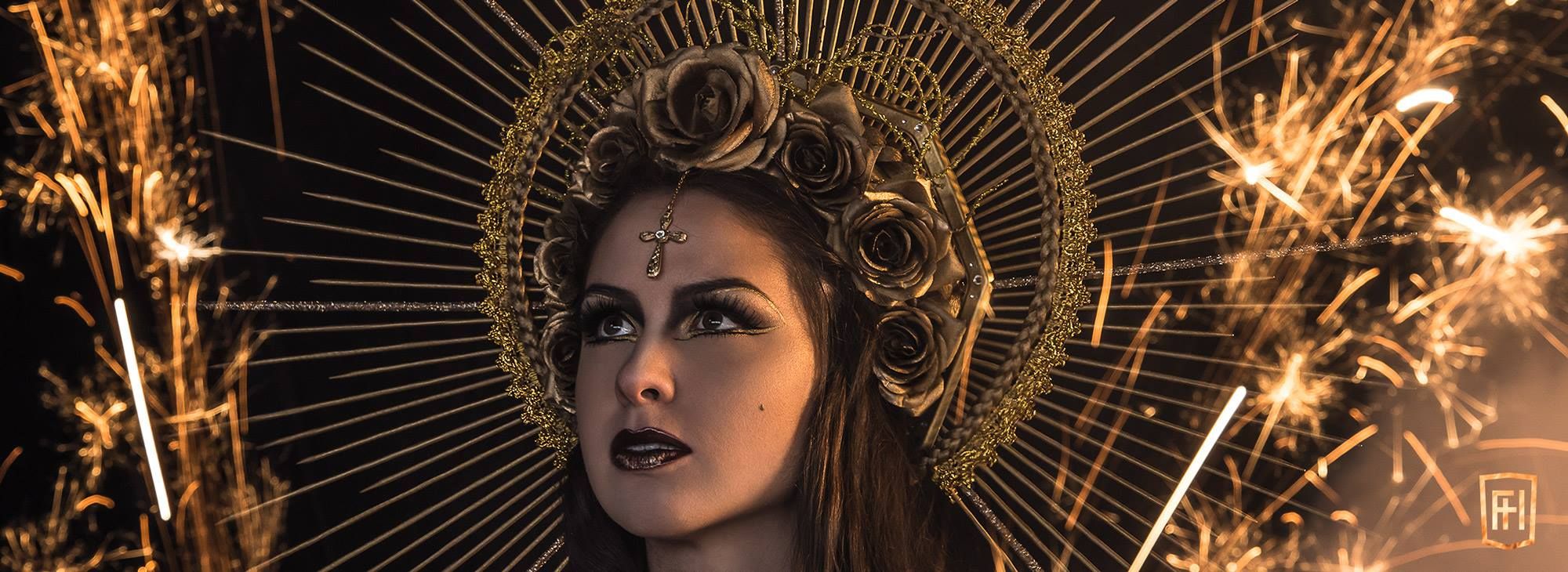 Evie Calypso in the golden headdress, framed by sparklers