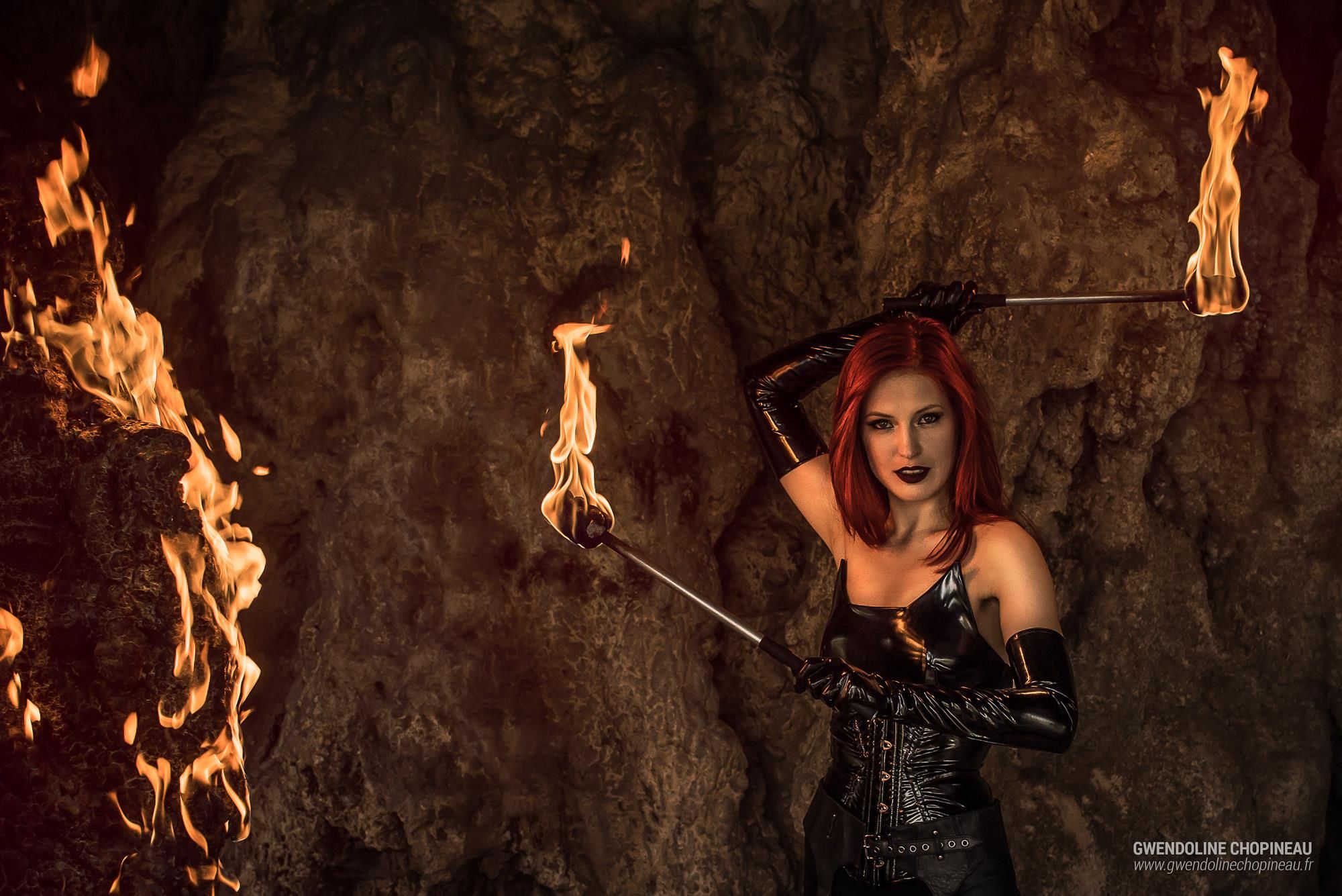 Ariel Firestone with two burning torches in a cave
