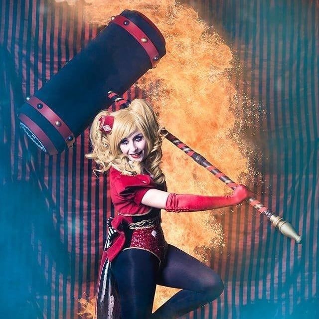 Cosplay Harley Quinn avec maillet, un mur de feu derrière